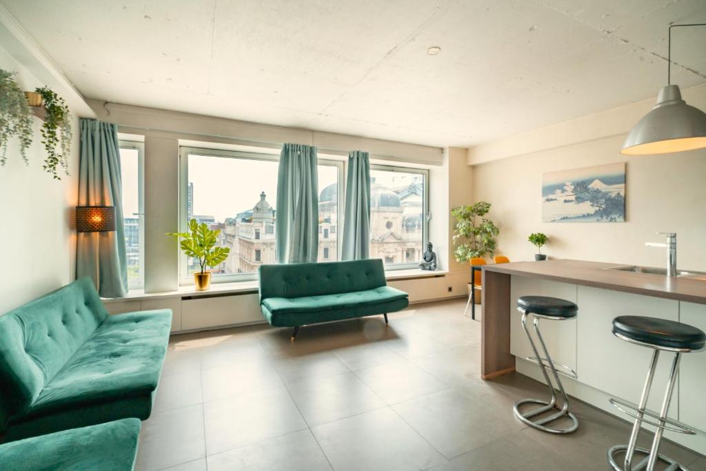 ein Wohnzimmer mit grüner Couch und einigen Fenstern in der Unterkunft Aspen Lodge in the Center of Antwerp in Antwerpen