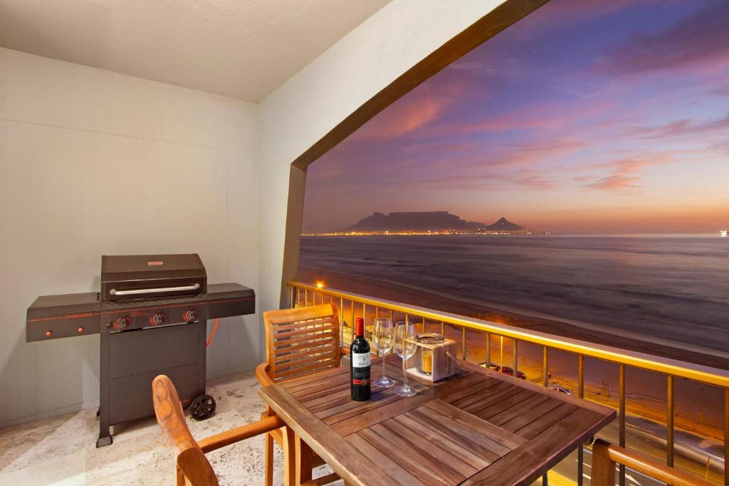 a balcony with a table and a view of the ocean at Luxury Beachfront 706 with AC, Workspace & Table Mountain Views in Cape Town