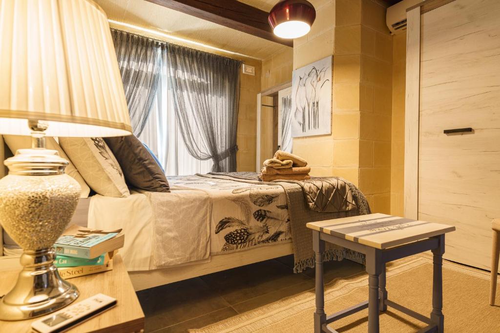 a bedroom with a bed and a table with a lamp at Ajuga Luxury Boutique B&B in Qala