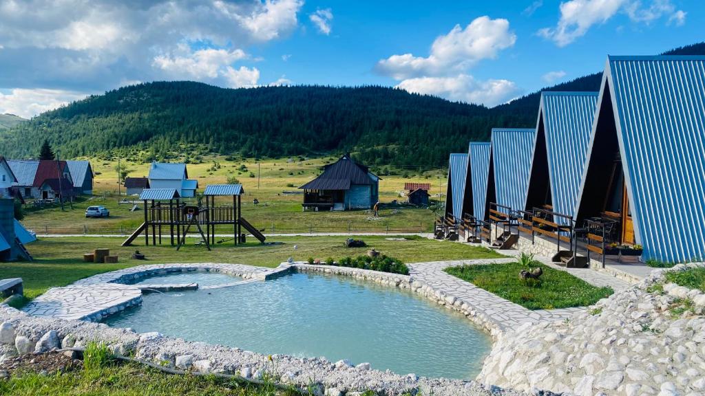 a large pool of water in a field with houses at Eco Village Pavlovic in Žabljak