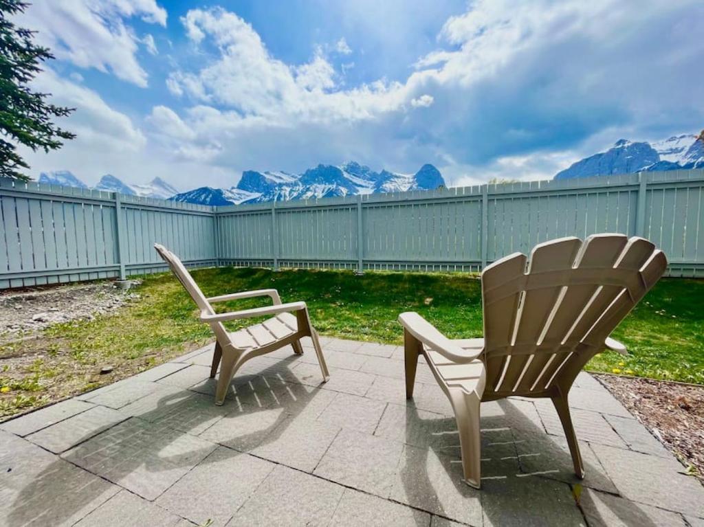 two chairs sitting on a patio with mountains in the background at Nakiska, 2 Bed 1 Bath with Mtn Views in Canmore