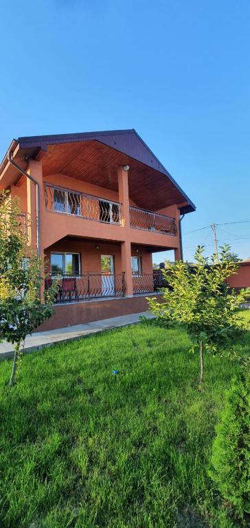 a house with a balcony and a green yard at Casa Valentin in Corbu