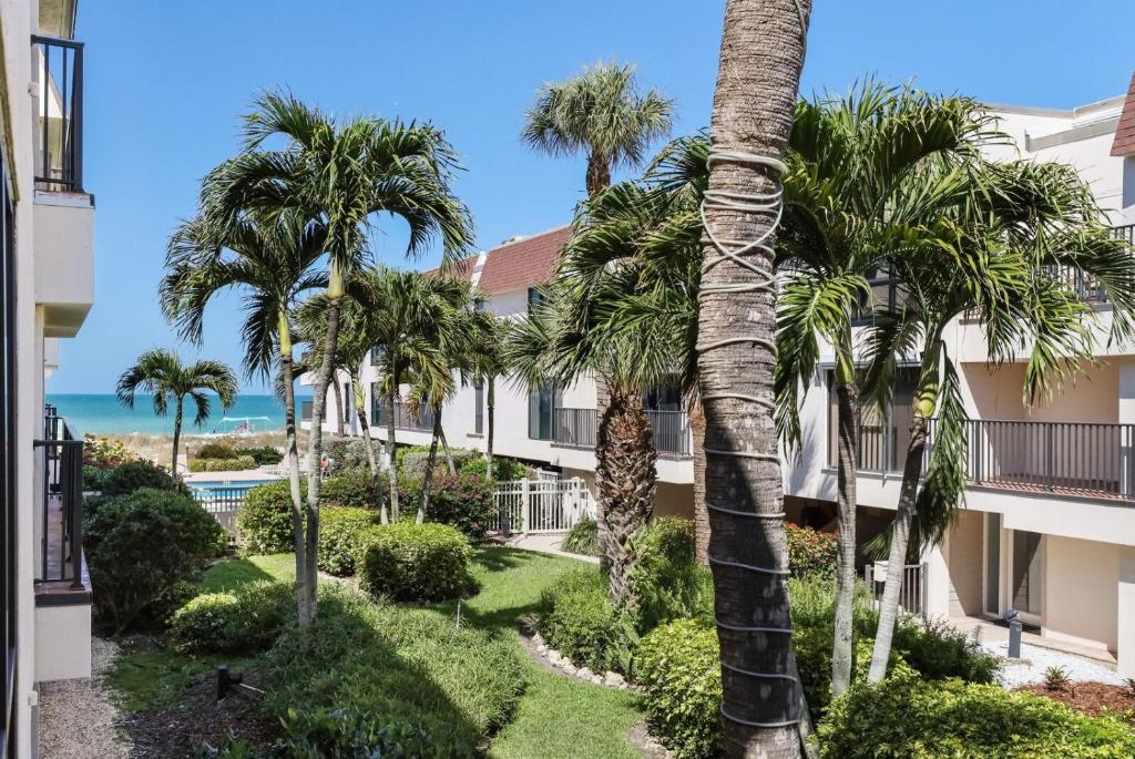 a view of a building with palm trees and the ocean at Waters Edge 104S condo in Holmes Beach