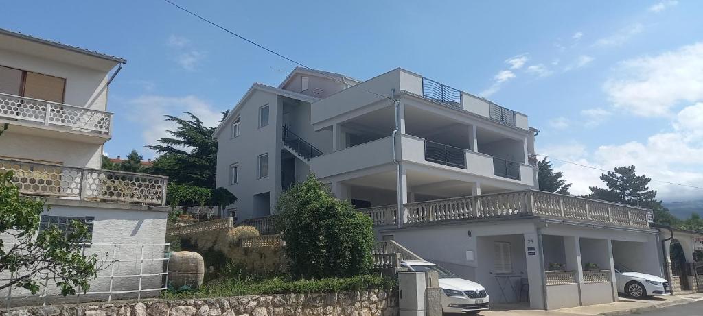 a white apartment building with a car parked in front of it at Apartmani Biba in Novi Vinodolski