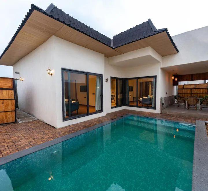 a swimming pool in front of a house at Palm Villas in Amritsar