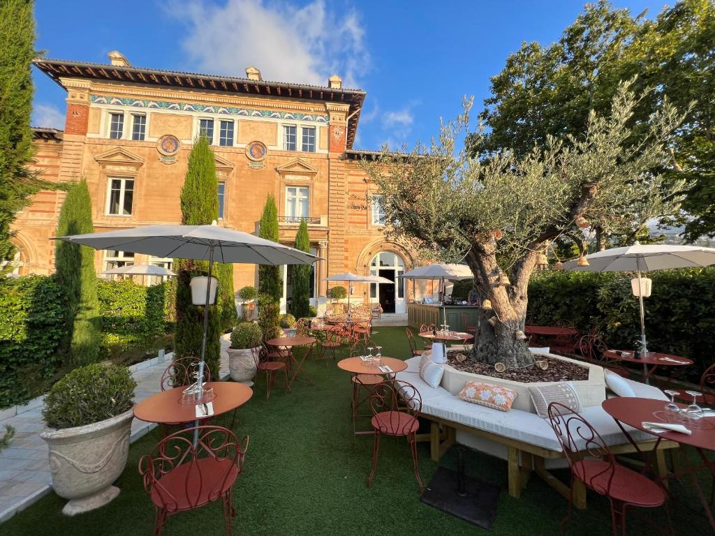 a courtyard with tables and chairs and a tree at Boutique Hôtel Château Beaupin Restaurant & Wellness in Marseille