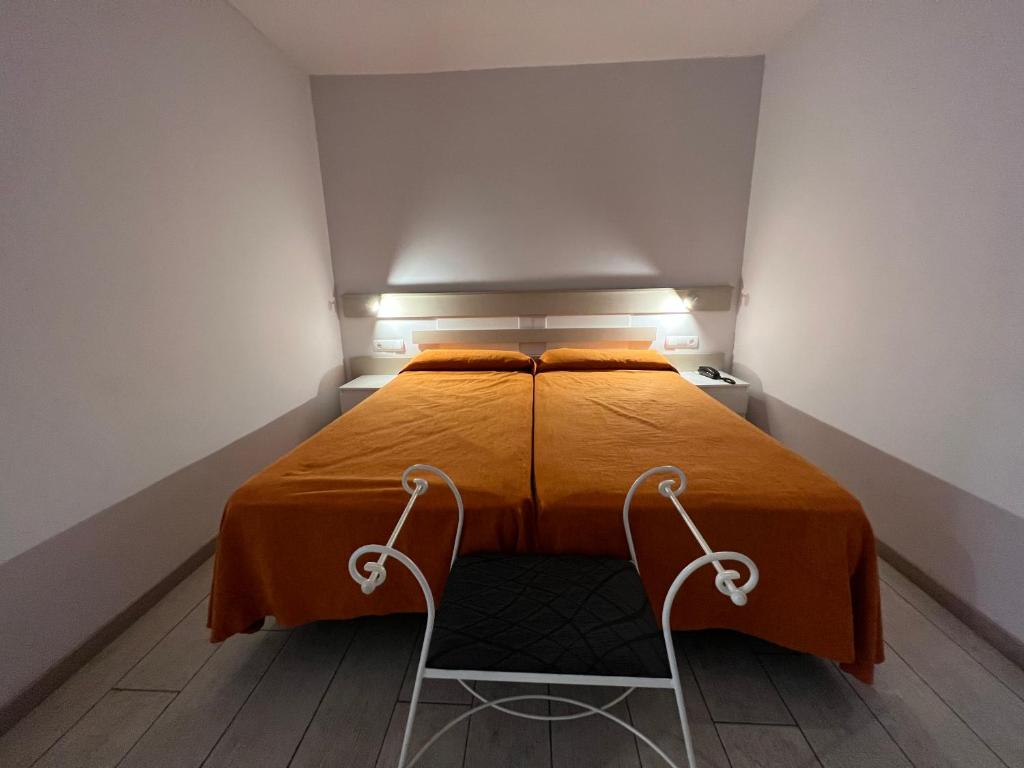 uma cama com duas cadeiras num pequeno quarto em Apartamentos Comfort Calella em Calella