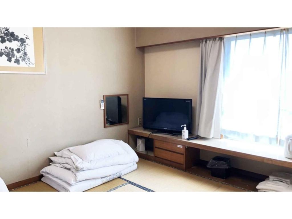 a living room with a tv and a bed and a window at Kagetsu Ryokan - Vacation STAY 04876v in Shizuoka