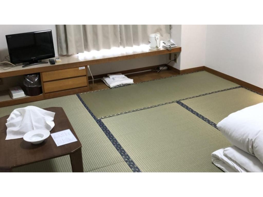 a hotel room with a bed and a table and a television at Kagetsu Ryokan - Vacation STAY 04023v in Shizuoka