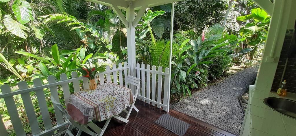 a porch with a table and a white fence at Les Gîtes de la Lézarde in Petit-Bourg