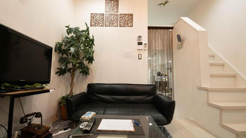 a living room with a black leather couch and a staircase at Designer's apartment polaris 101 - Vacation STAY 13314 in Nagoya