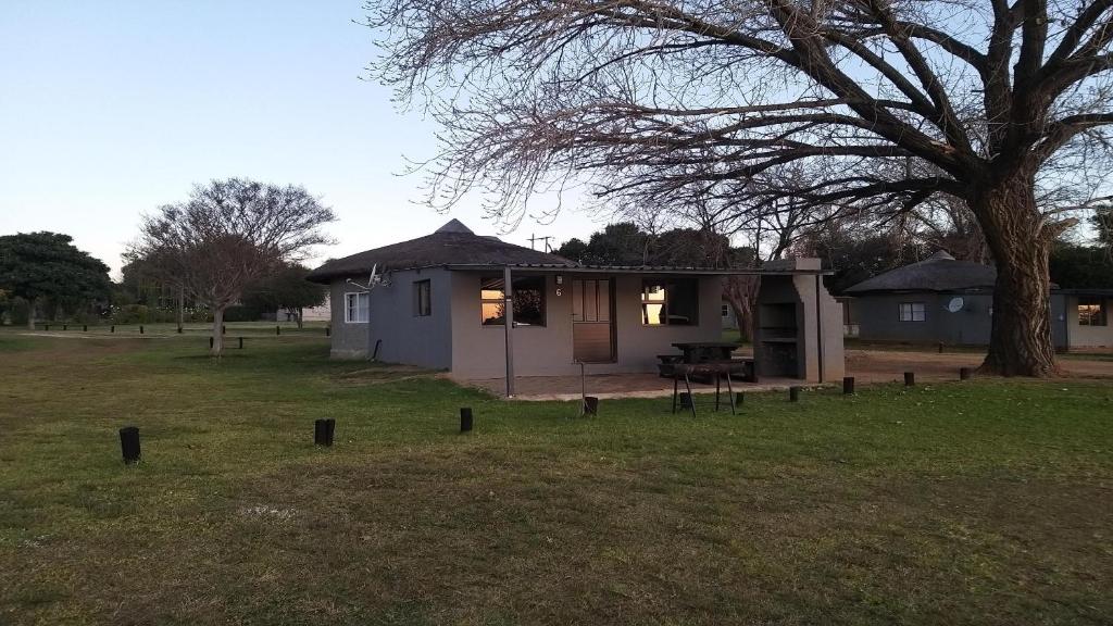 una pequeña casa en un campo con un árbol en Vaal Marina Resort en Vaal Marina