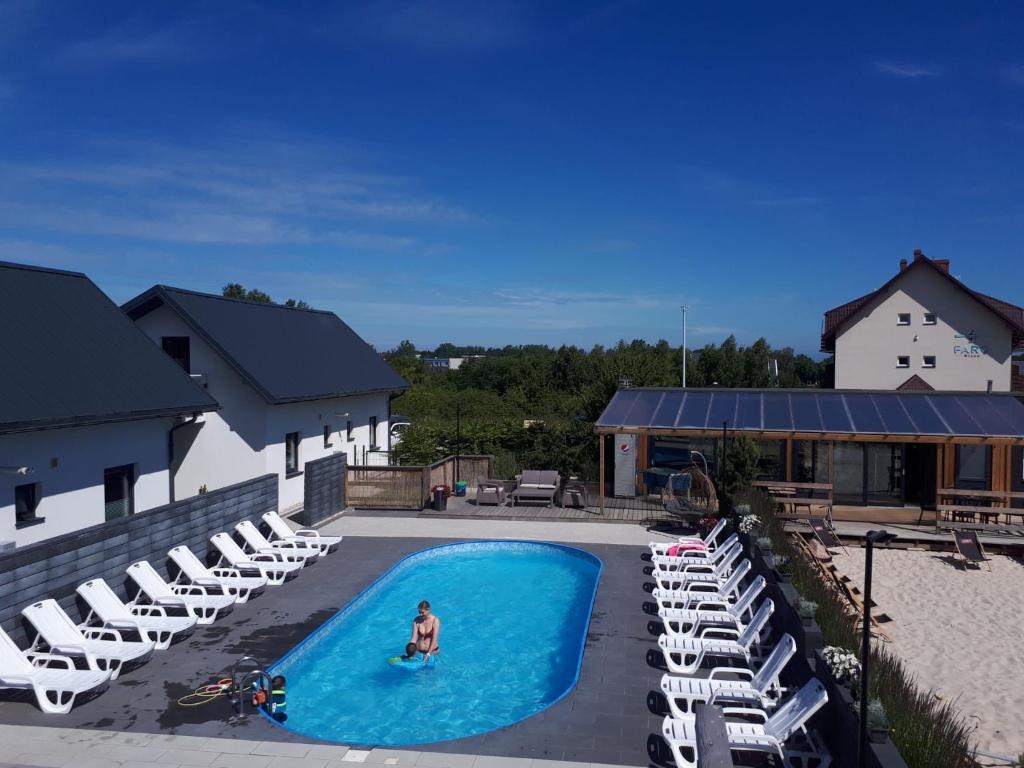 a woman in a swimming pool with chairs and a person in the water at Domki Borys in Jastrzębia Góra