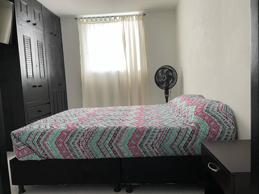 1 dormitorio con 1 cama con una manta colorida y una ventana en Confortable Apartamento en Ibagué con piscina solo Fines de semana solo para FAMILIAS, en Ibagué