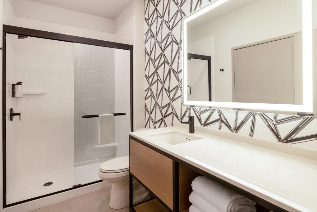 ein Badezimmer mit einem Waschbecken, einem WC und einem Spiegel in der Unterkunft Atwell Suites - DENVER AIRPORT TOWER ROAD, an IHG Hotel in Denver