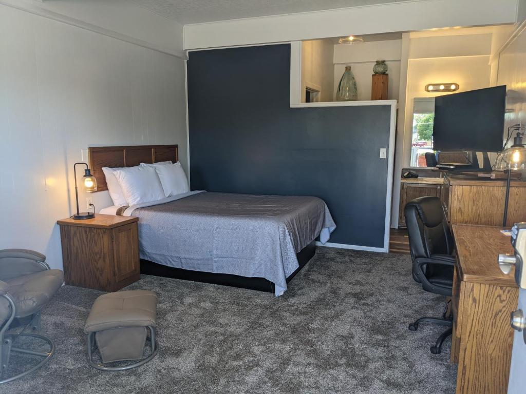 Schlafzimmer mit einem Bett, einem Schreibtisch und einem TV in der Unterkunft The Oakwood Inn in Sterling