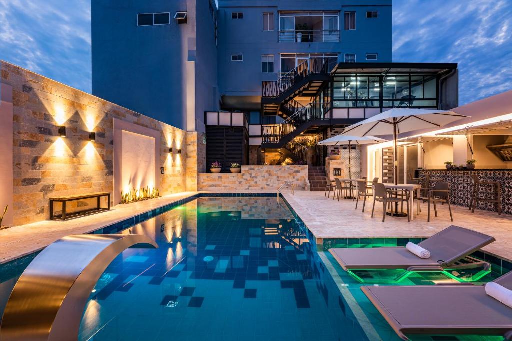 una piscina con mesas y sillas junto a un edificio en Hotel Elite, en Barrancabermeja