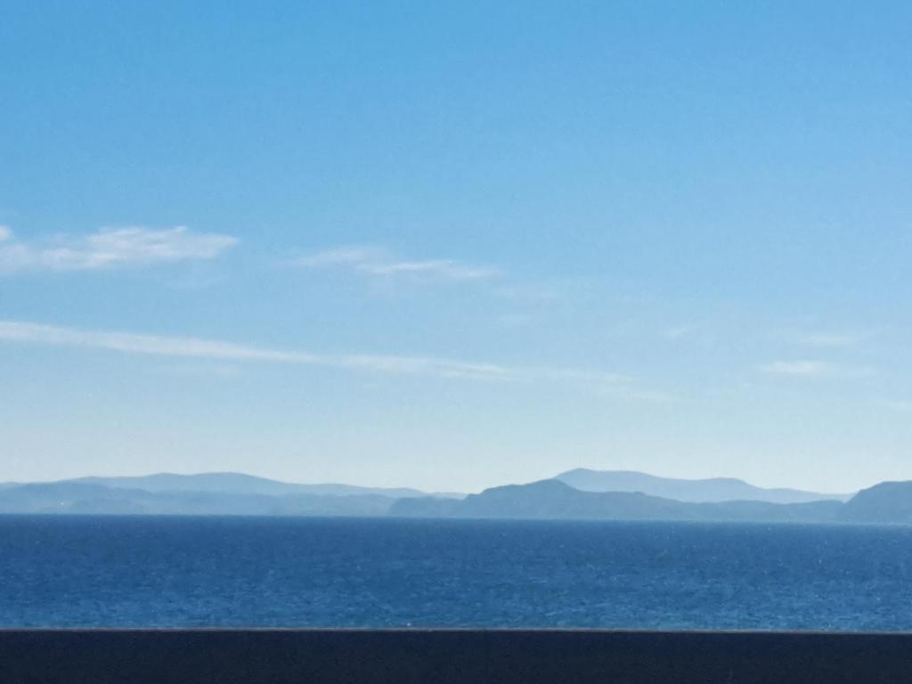 a view of the ocean with mountains in the distance at Logan Home in Stornoway