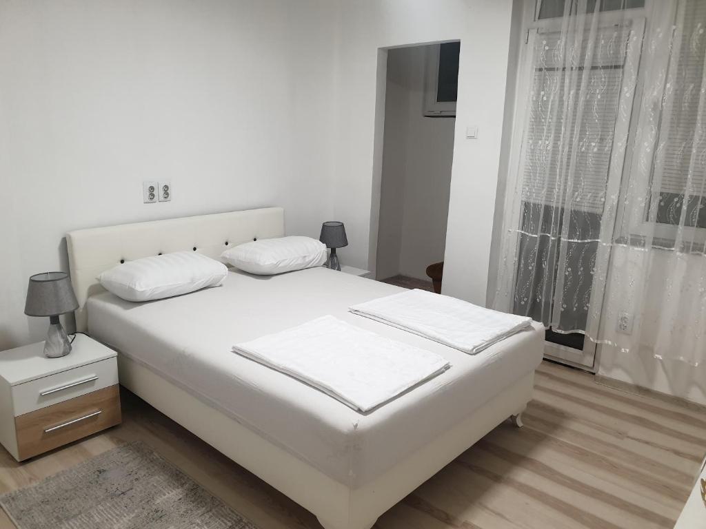 a white bedroom with a white bed and a window at Apartman Lana in Bosanski Novi