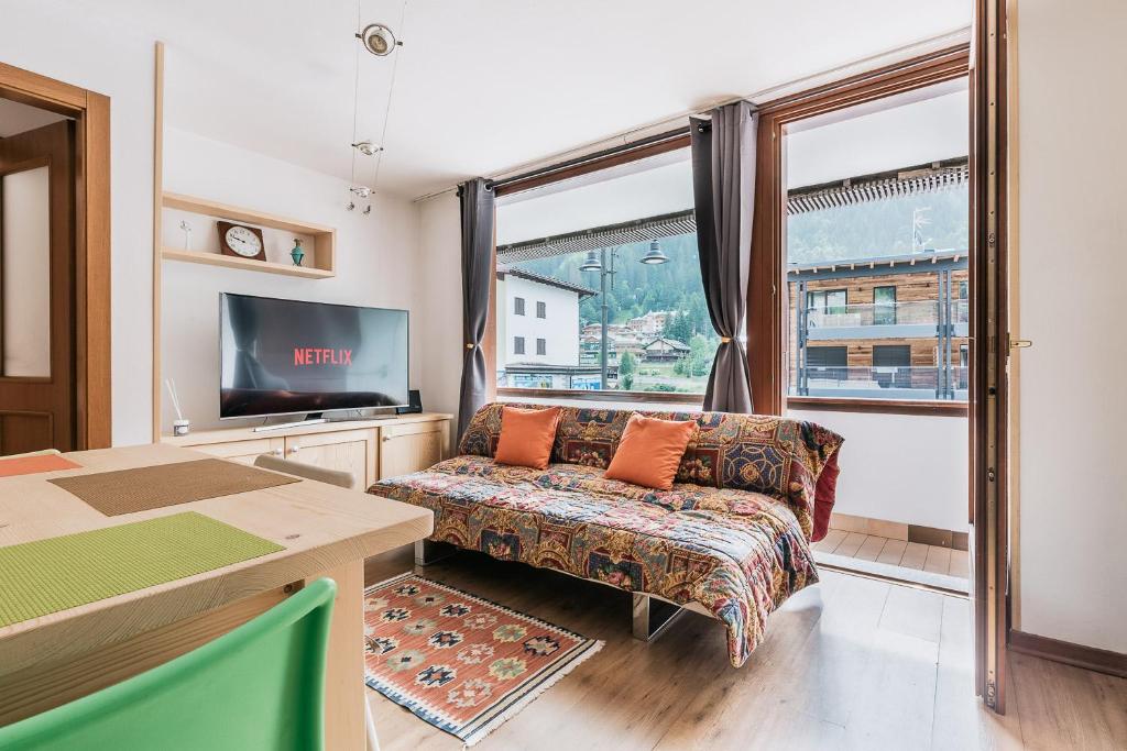 sala de estar con sofá, TV y ventana en [Campiglio-Apartment] Free Parking & Self Check-in, en Madonna di Campiglio