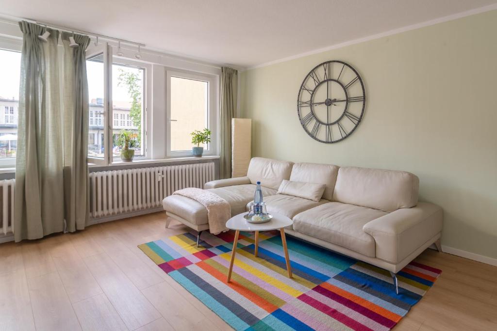 a living room with a couch and a clock on the wall at Akram Appartement I - Zentral und Ruhig in Hildesheim
