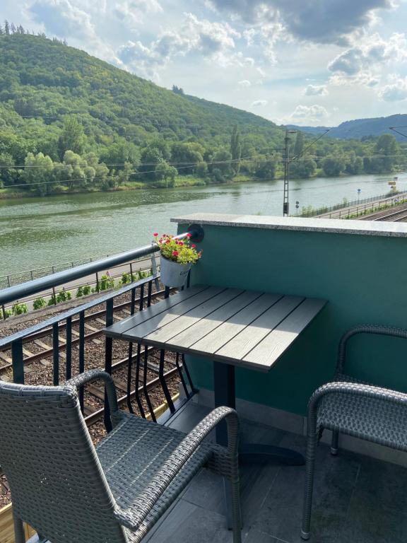 a table and chairs on a balcony with a view of a river at Haus Elsternest in Klotten
