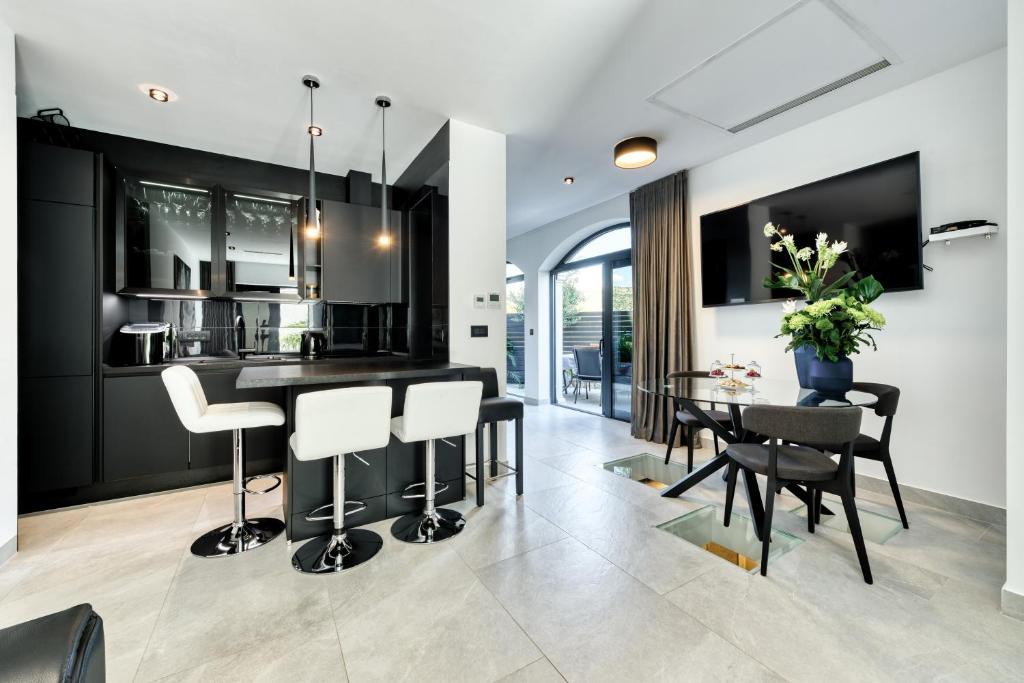 eine Küche mit schwarzen Schränken sowie einem Tisch und Stühlen in der Unterkunft Apartment One B with Heated Outdoor pool in Dubrovnik