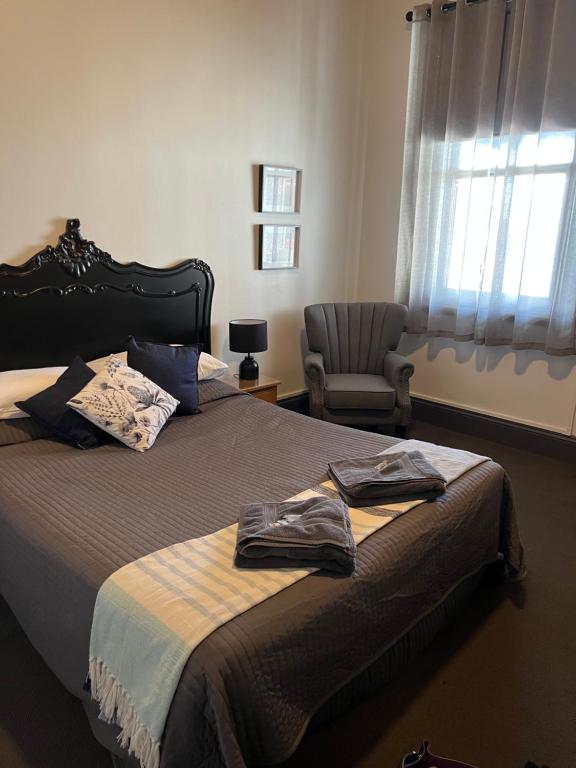 a bedroom with a bed with a chair and a window at Oriental Hotel Tumut in Tumut