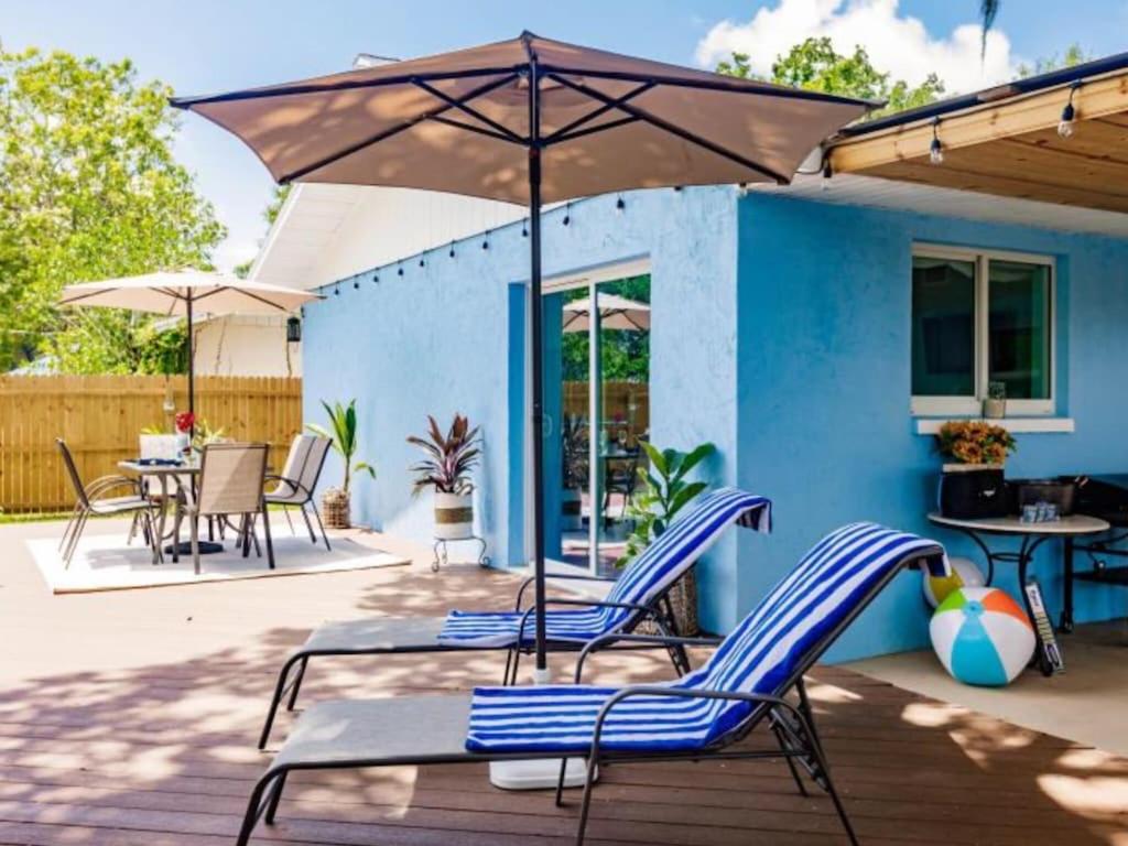 un patio con sillas, mesas y una sombrilla en Blue vacation house, en Venice