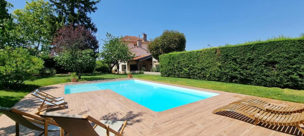 een zwembad met een tafel en stoelen en een huis bij Exclusif - Splendide villa 6ch à 15min de Lyon in Rillieux