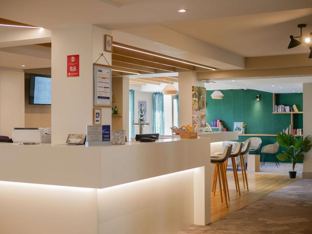 a lobby with a white counter with stools at Best Western Le Bois de la Marche in Poitiers