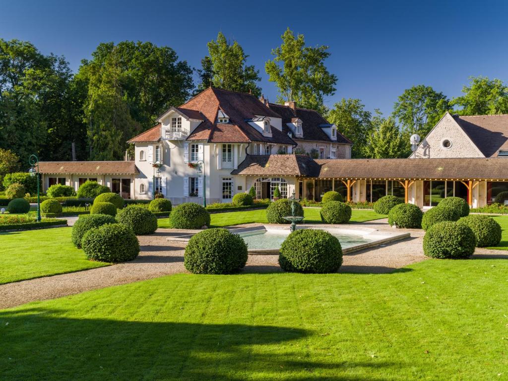 una gran casa blanca con un patio con arbustos en Hostellerie De Levernois en Levernois