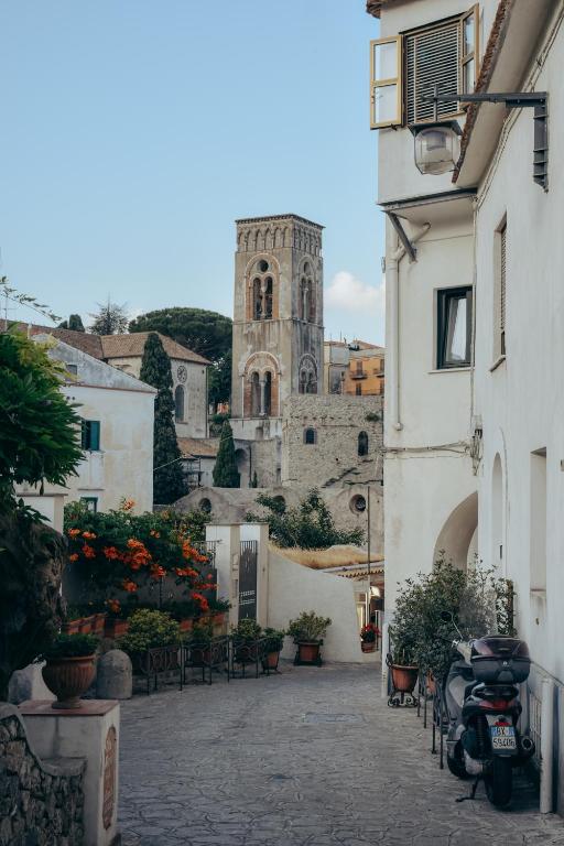 budynek z wieżą i kościołem w tle w obiekcie Il Centro Storico Ravello w mieście Ravello