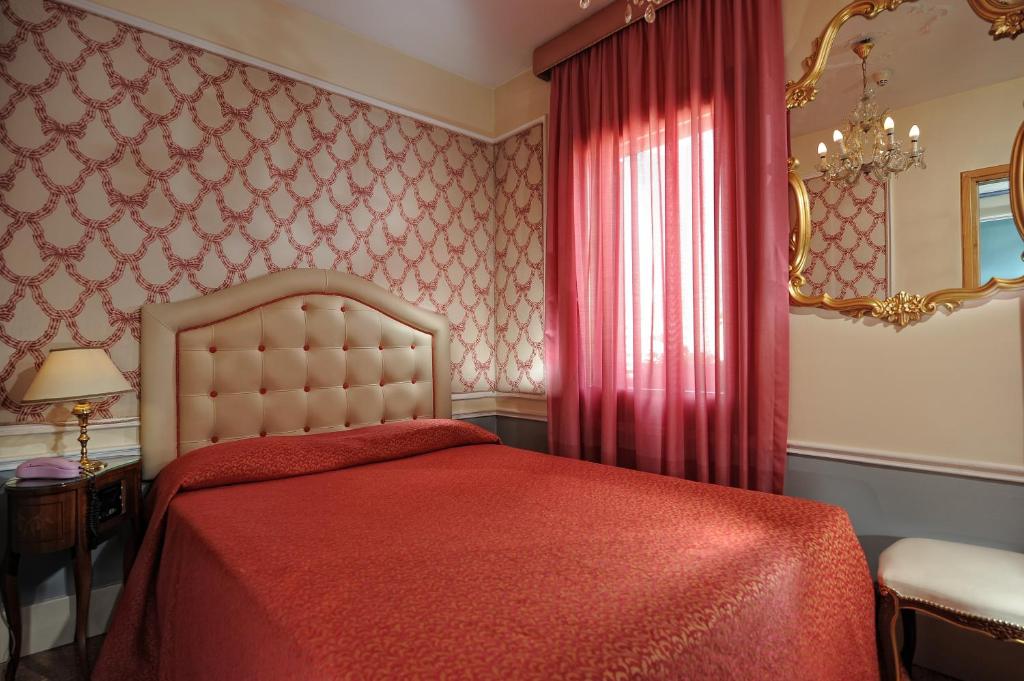 a bedroom with a red bed with a red blanket at Hotel Arlecchino in Venice
