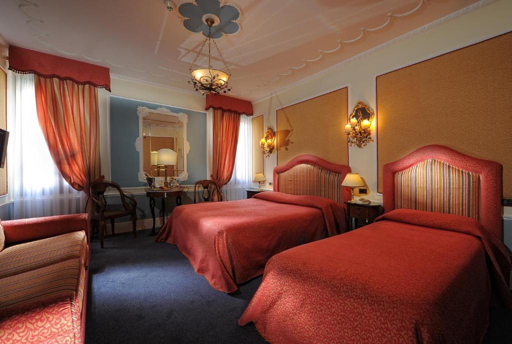 a hotel room with two beds and a table at Hotel Arlecchino in Venice