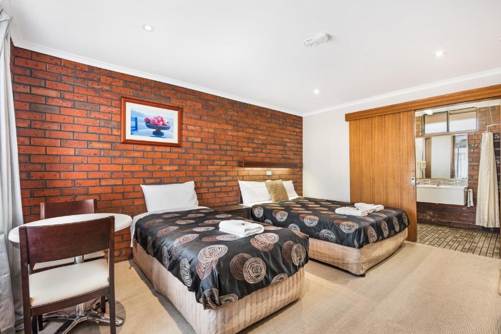 1 dormitorio con 2 camas y pared de ladrillo en Golden Country Motel and Caravan Park, en Maryborough