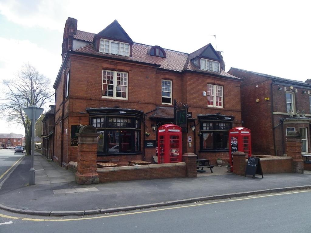 um edifício de tijolos com três cabines telefónicas vermelhas numa rua em Fifteens of Swinley em Wigan