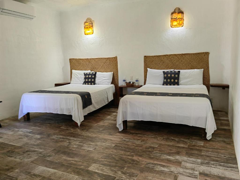 Habitación con 2 camas, sábanas blancas y lámparas. en VILLA DEL PEZ en Sayulita