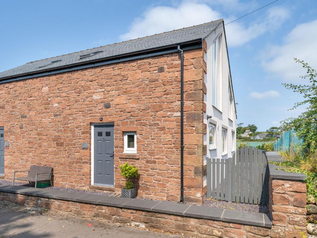 a brick building with a door and a bench at Coney Garth Retreat in Beckermet