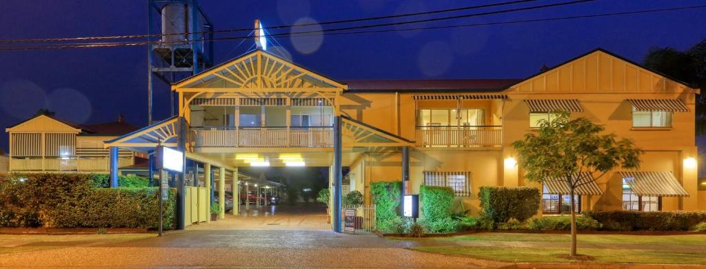 un gran edificio amarillo por la noche con en Dalby Homestead Motel en Dalby