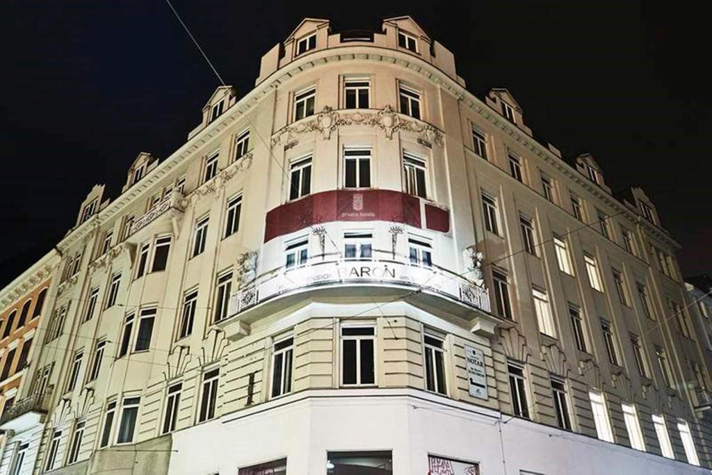 duży biały budynek z biało-czerwonym w obiekcie Hotel Pension Baron am Schottentor w Wiedniu
