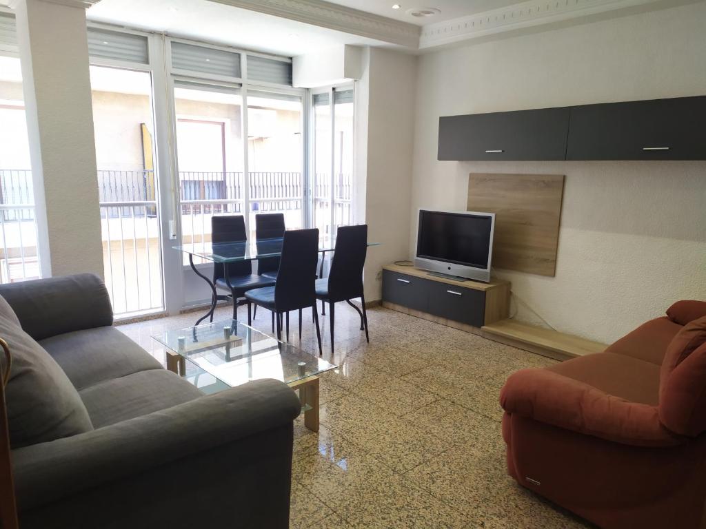 a living room with a table and chairs and a television at Major del Pla 25 in Elche