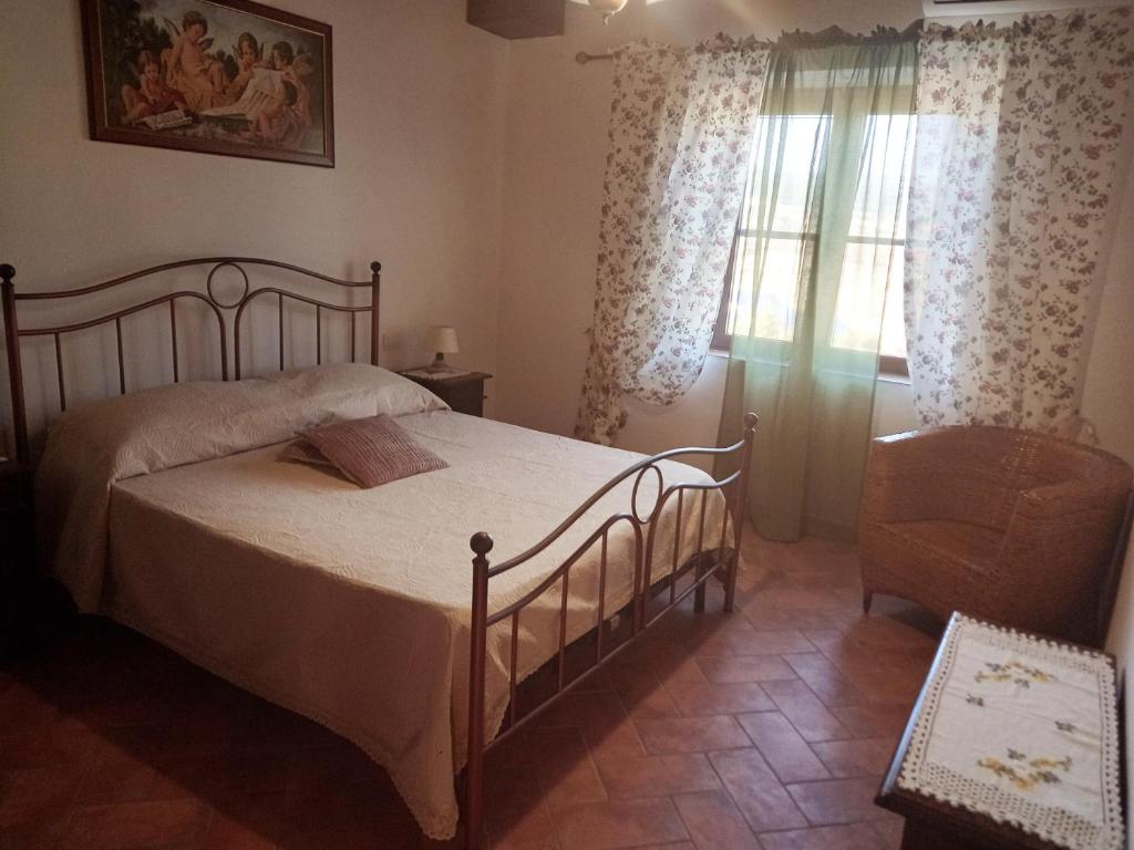 um quarto com uma cama, uma cadeira e uma janela em Agriturismo La Casina em Saturnia