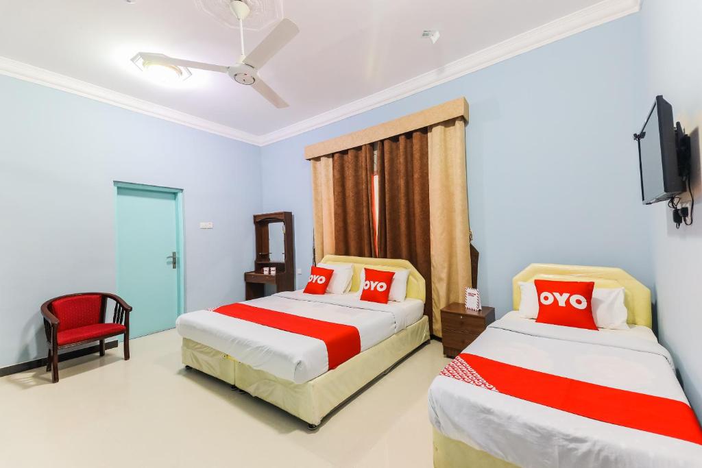 a hotel room with two beds and a tv at Super OYO 110 Ras Al Hadd Guest House in Al Ḩadd