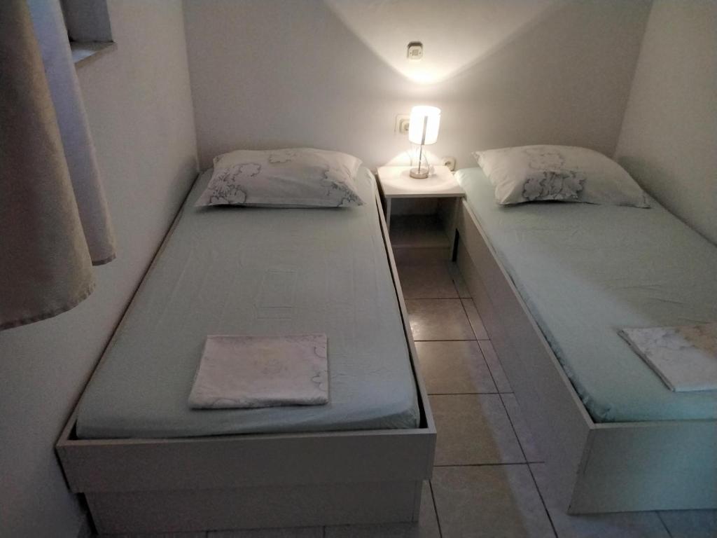 two twin beds in a small room with a lamp at Apartmani Erceg in Jadrija