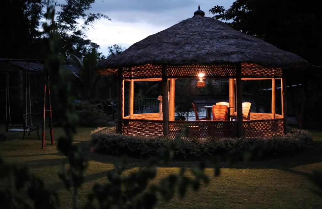 a gazebo with a thatch roof at night at Bononi in Jorhāt