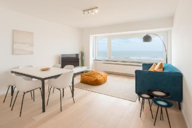 a living room with a table and chairs and a window at Prachtig Zeezicht Appartement in Ostend