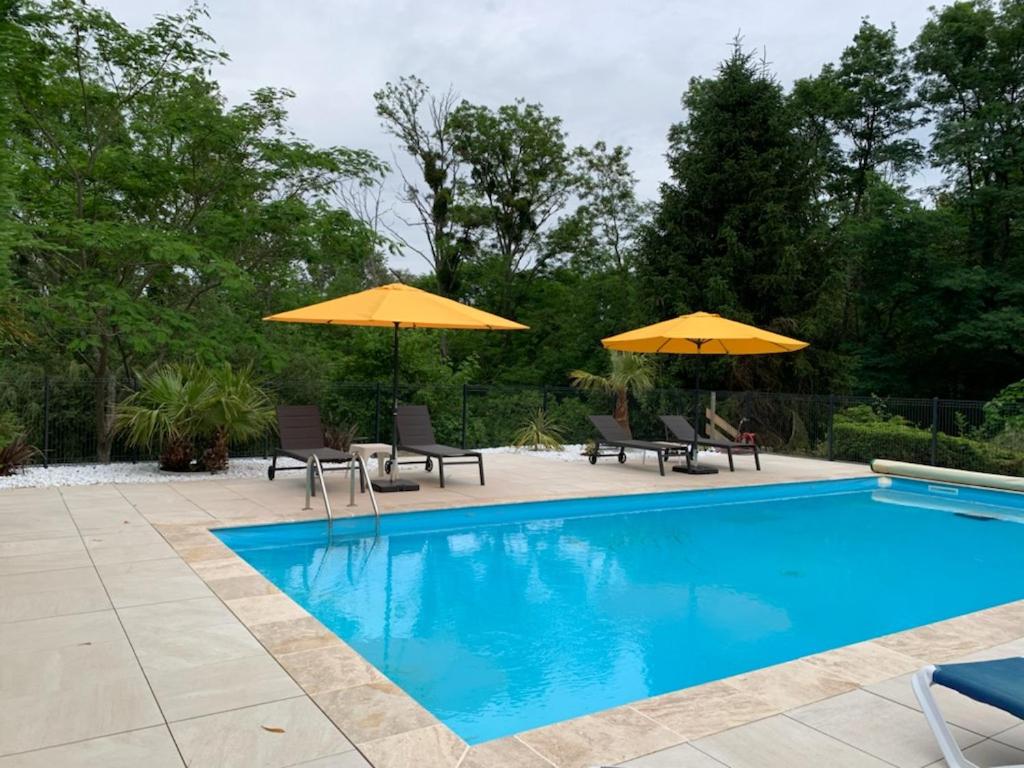 una piscina con due ombrelloni e sedie gialli di Gites Matilon, 5 min Eugénie les bains a Buanes