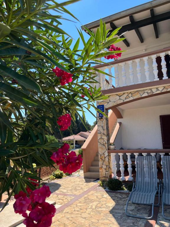 a tree with pink flowers in front of a house at Apartmani Hranjec in Ugljan