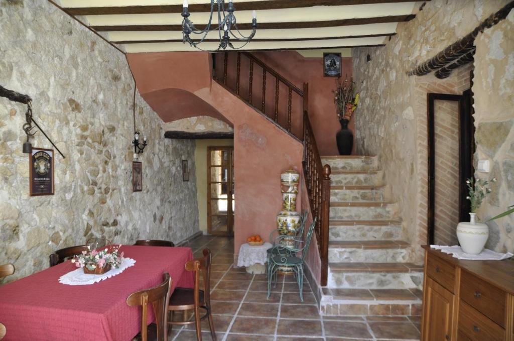 a dining room with a red table and stairs at Aljibe de Monastrell in Ricote